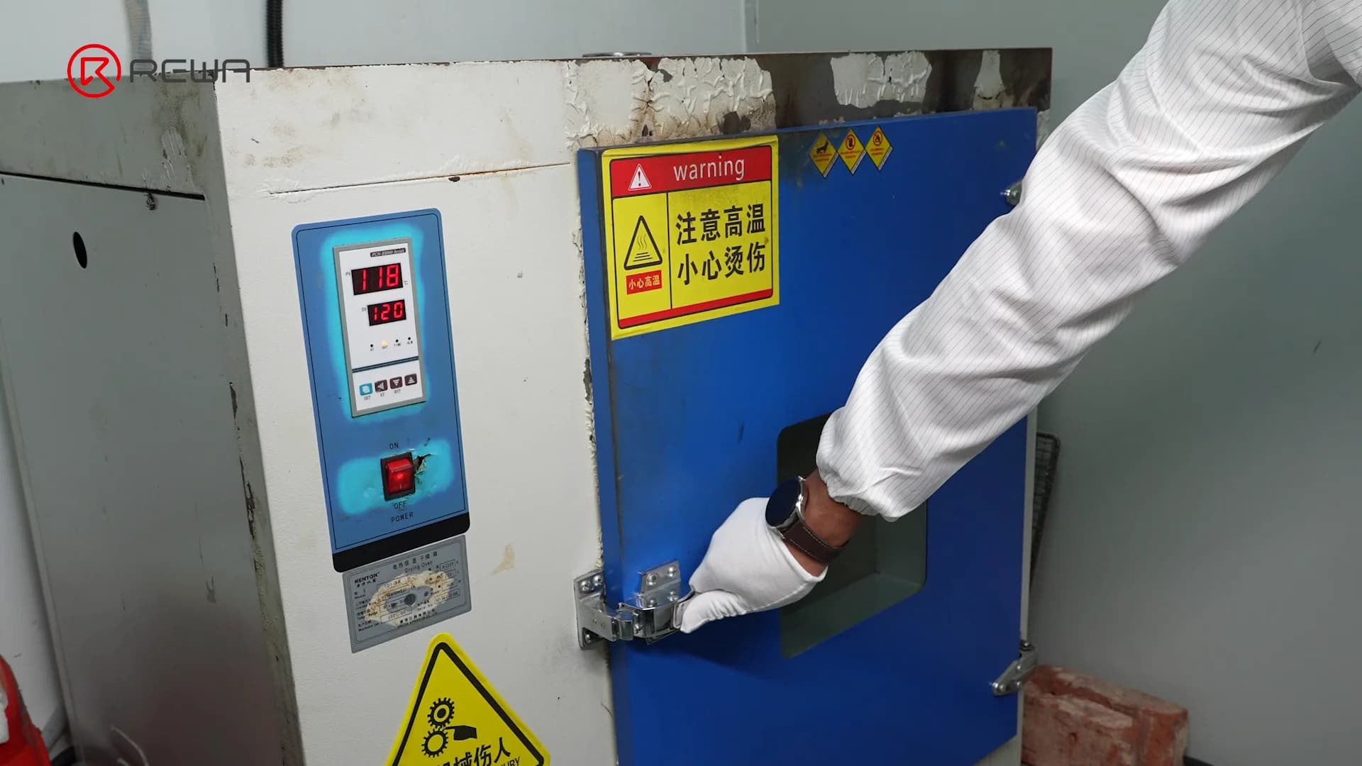 A gloved worker closing the door of an industrial drying oven used to cure underfill adhesive