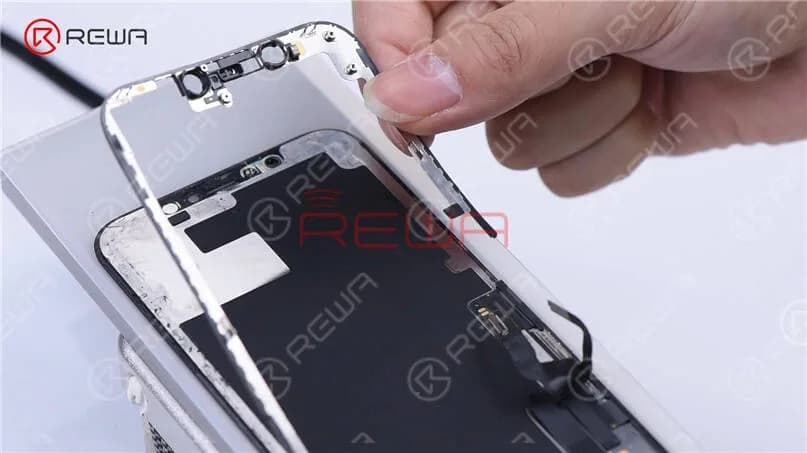 As the ear speaker flex cable part has more adhesive, we can dip more adhesive remover to make it loose. Hold the two corners of the bezel in both hands, and detach the bezel slowly with caution. Our original thought was to separate the bezel in a complete manner and then reuse it. But now the bezel is broken here. So please notice that this part of the bezel is made of plastic material, which is extremely easy to break. If you want to separate the bezel completely, you need to pay extra attention.